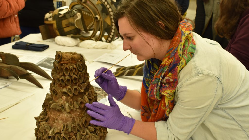 UCL Conservation student conducting visual inspect of headdress collected by N. W. Thomas for condition report